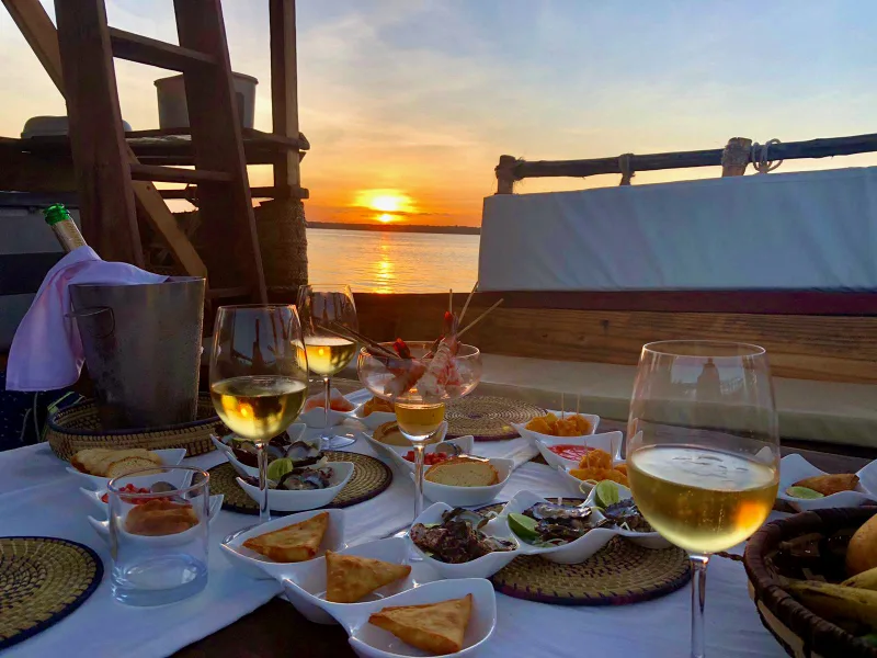 Gourmet bites, sparkling wine and chilled glasses laid out on board at sunset
